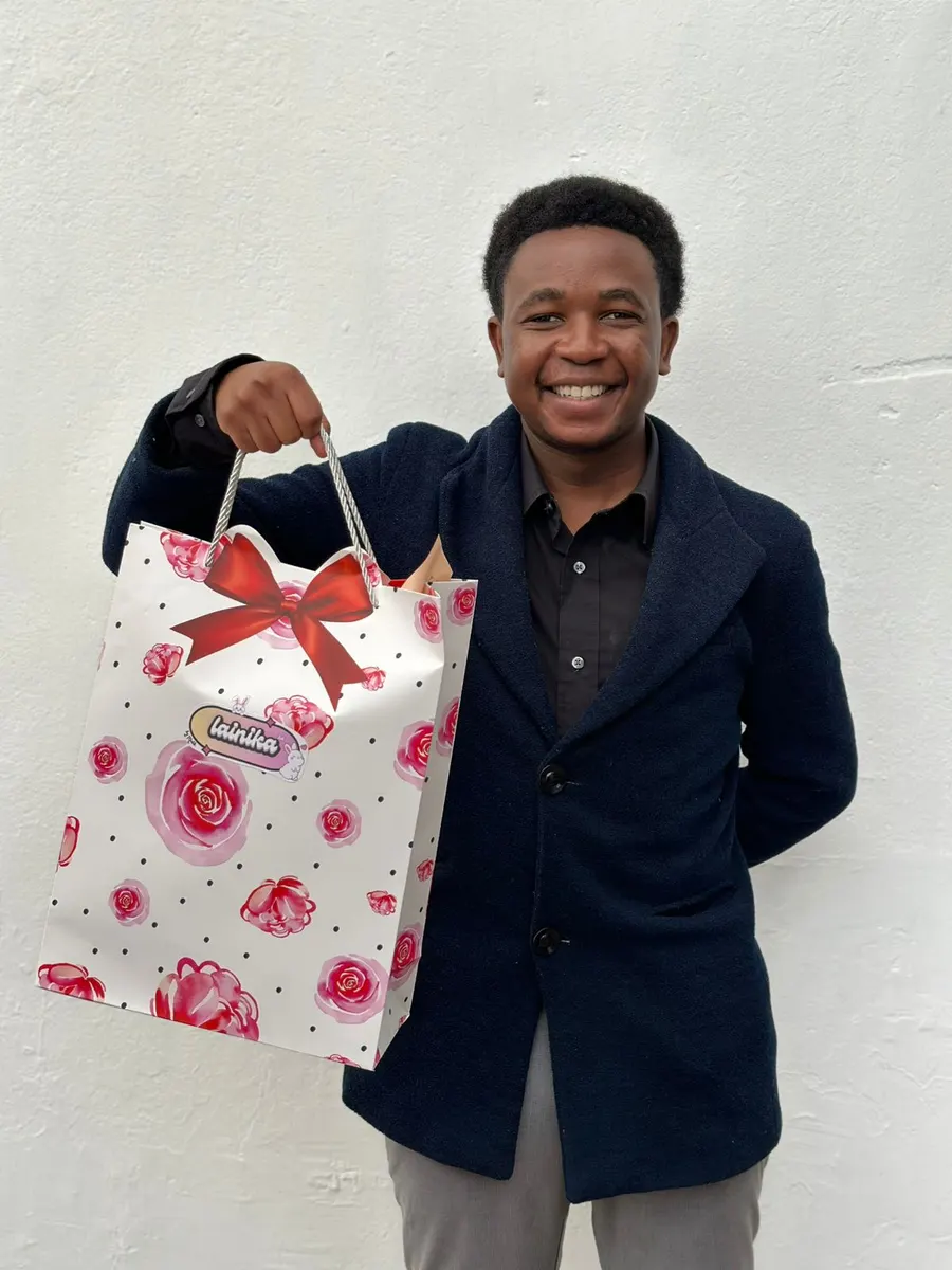 Guy smiling while holding a Lainika bag gift for his girlfriend