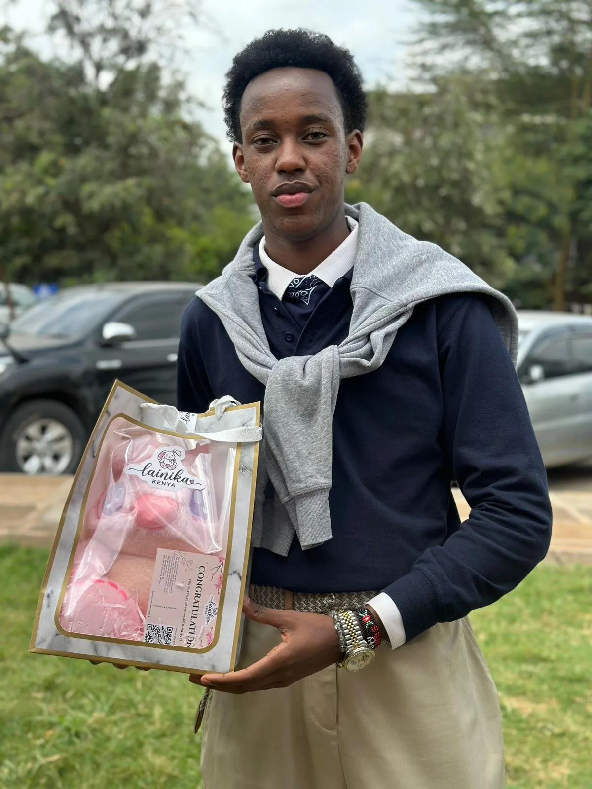 A young man smiling while holding a Lainika gift bag with a pink plushie visible inside