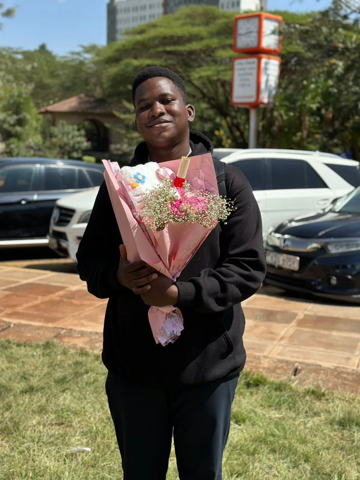 A young man smiling while holding a plush bouquet on a city street